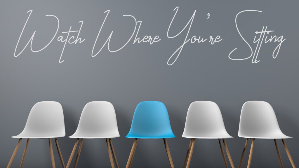 Three chairs with a blue chair standing out among white ones.