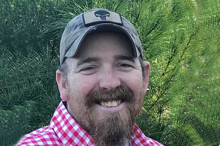 Man smiling with greenery background