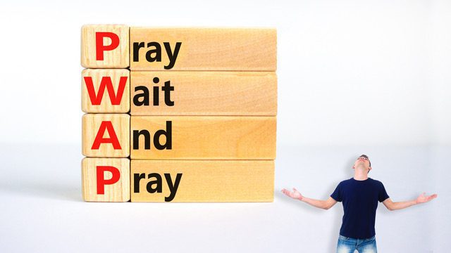 Child pointing at a wooden block tower spelling PRAY, WAIT, AND PRAY.