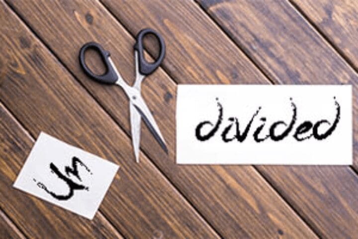 Scissors and divided paper on wood surface