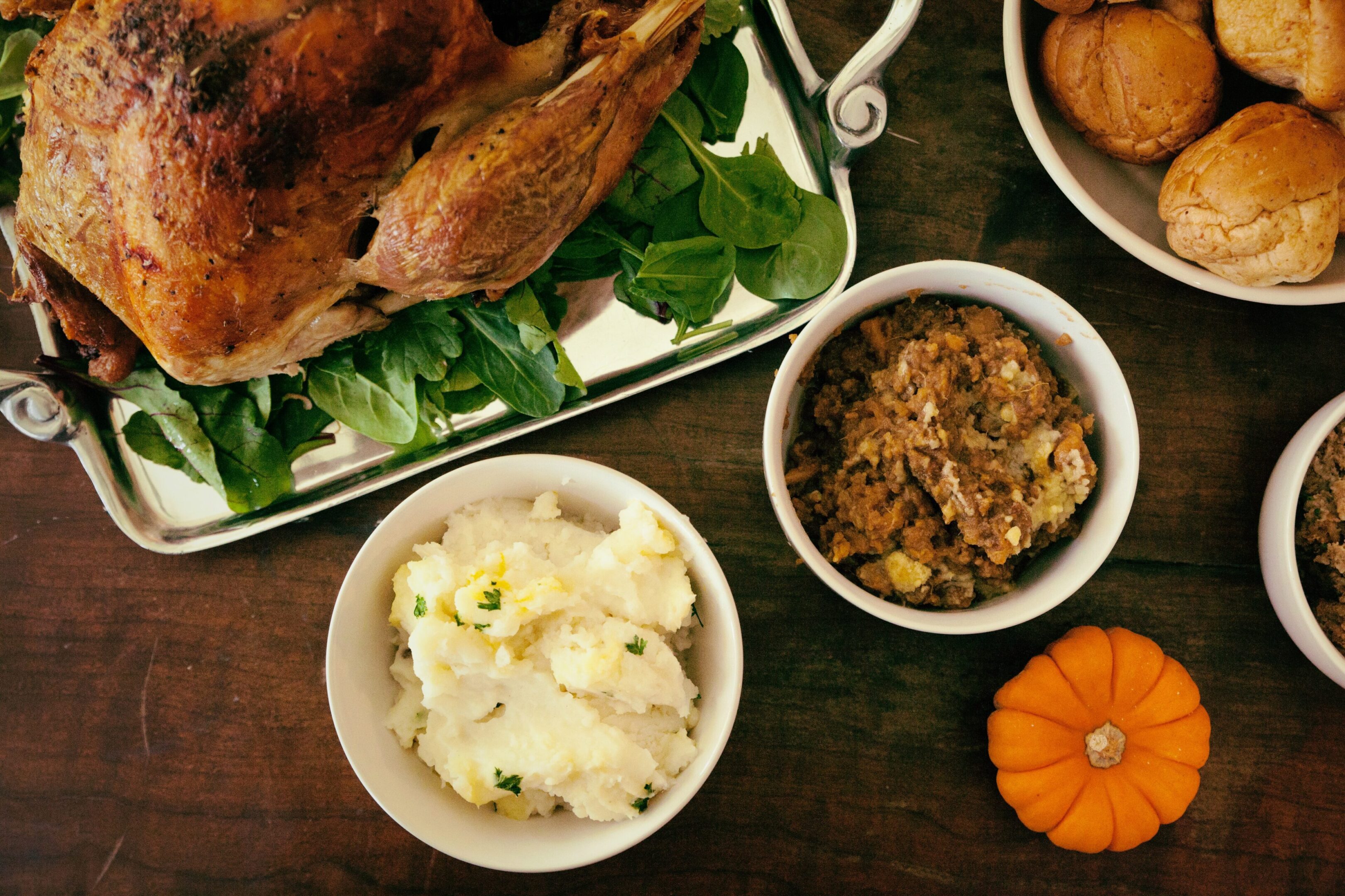 A Thanksgiving meal with turkey, mashed potatoes, stuffing, and a small pumpkin.