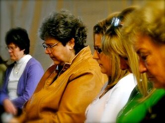 Four women sitting closely, appearing thoughtful or reflective.