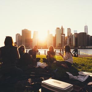 Friends enjoying a sunset picnic by the city skyline.
